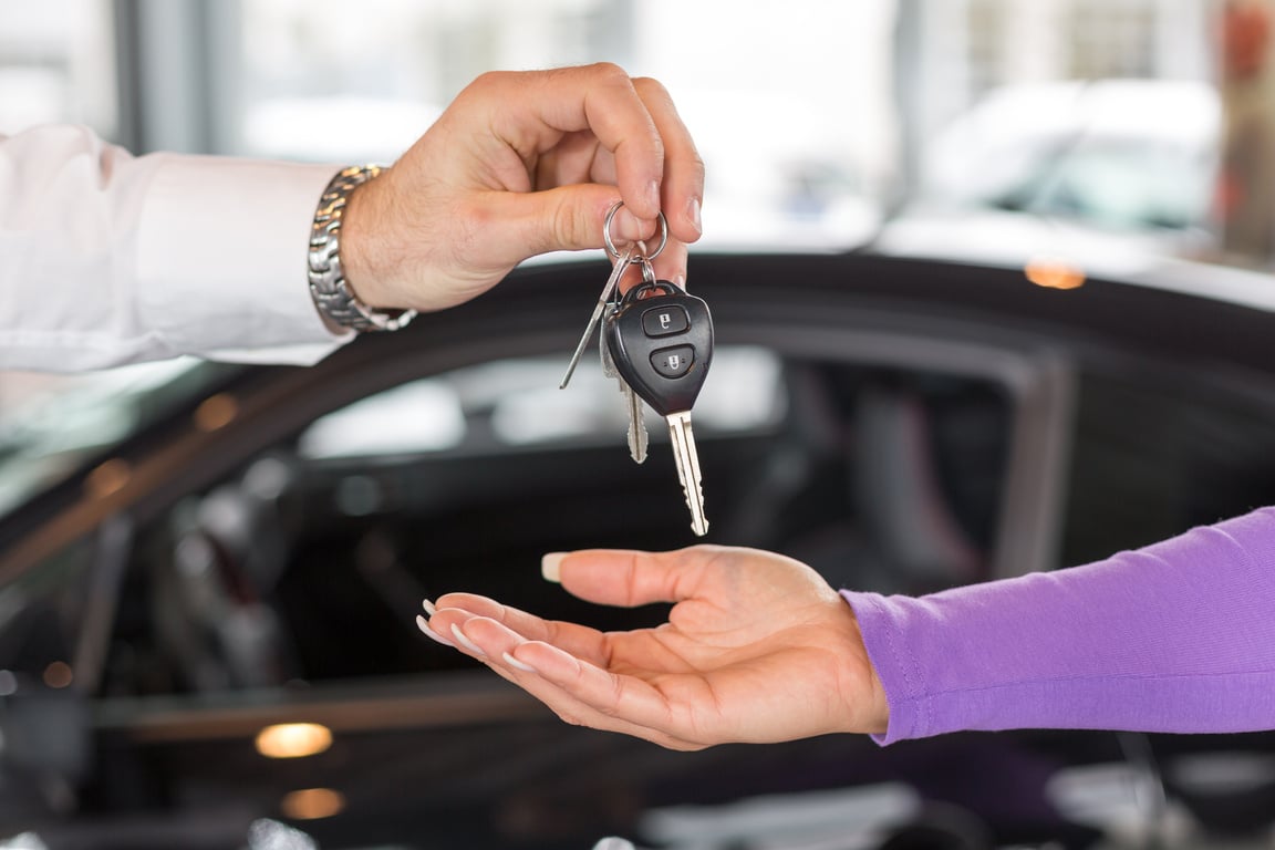 Salesman handing over car keys in dealership